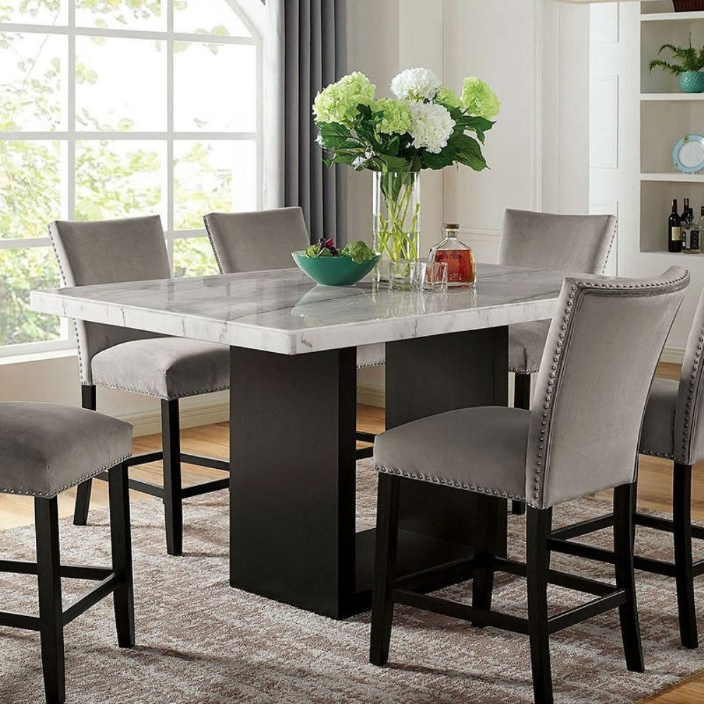 Genuine marble dining table with solid wood base at counter height, surrounded by six gray upholstered chairs in a modern dining room.