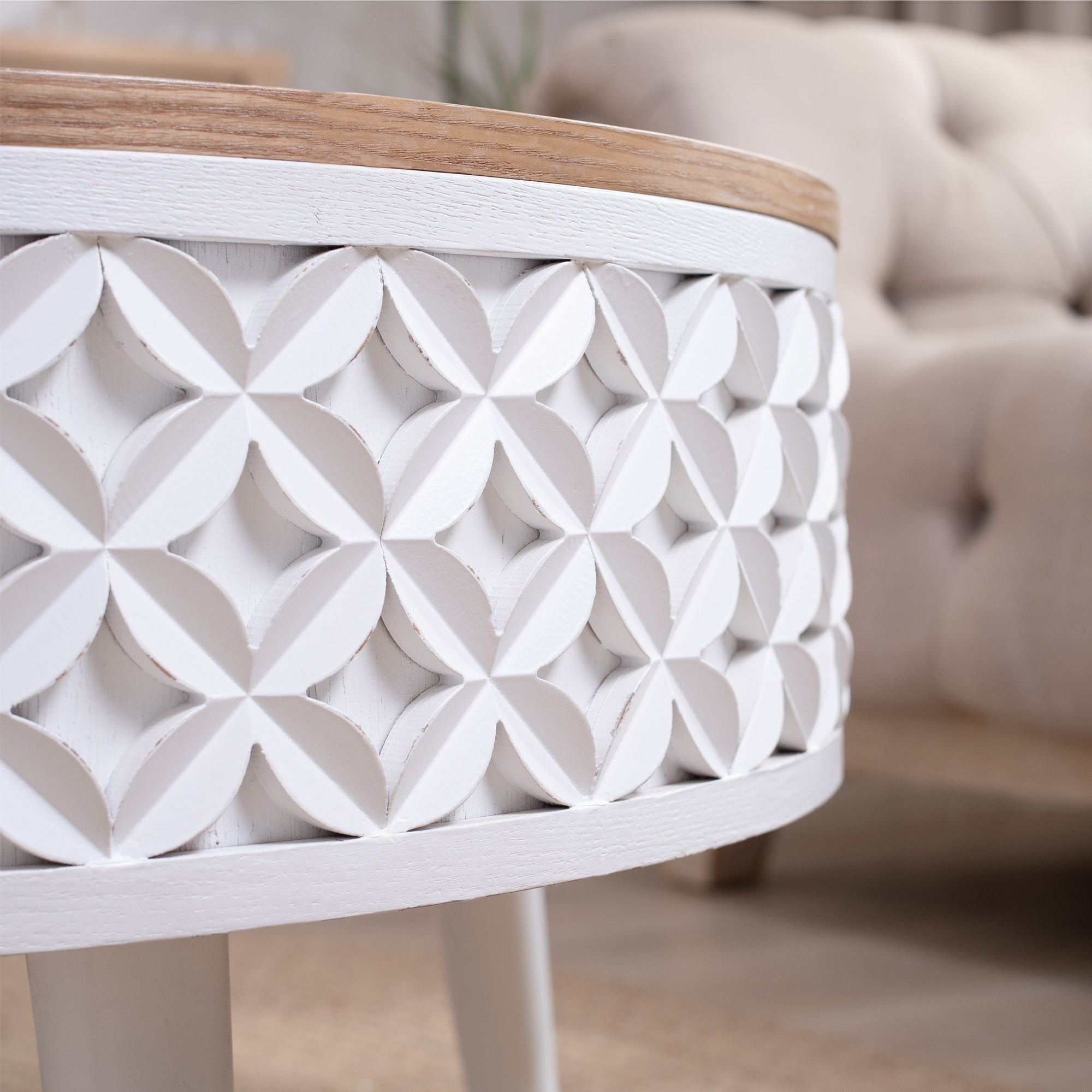 Detailed view of white carved geometric pattern on round coffee table base, paired with natural wood top.