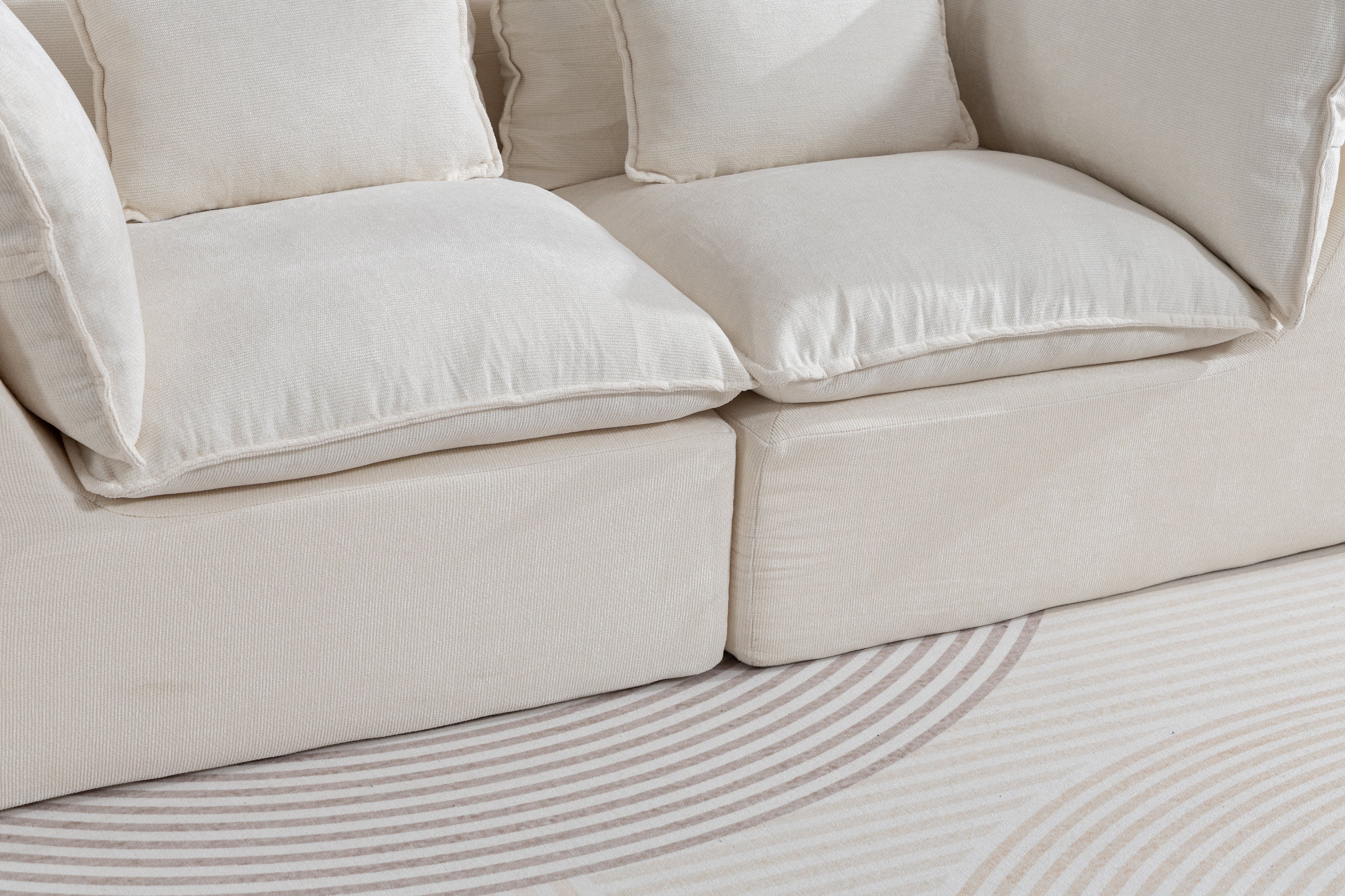 Close-up of oversized modular sectional sofa cushions showing plush, cloud-like comfort and soft velvet texture in cream color.