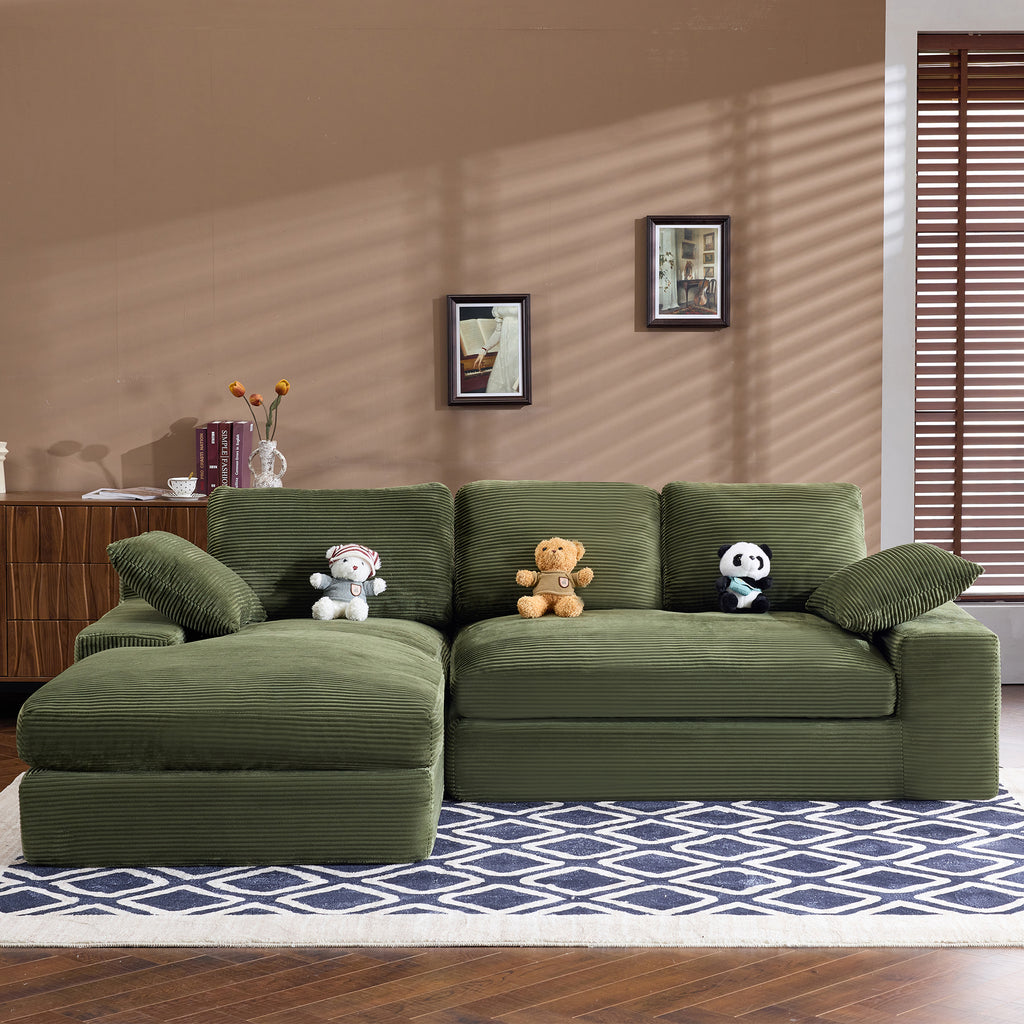 Green corduroy sofa with plush cushions and pillows, styled with stuffed toys. Compact and stylish for modern home interiors.