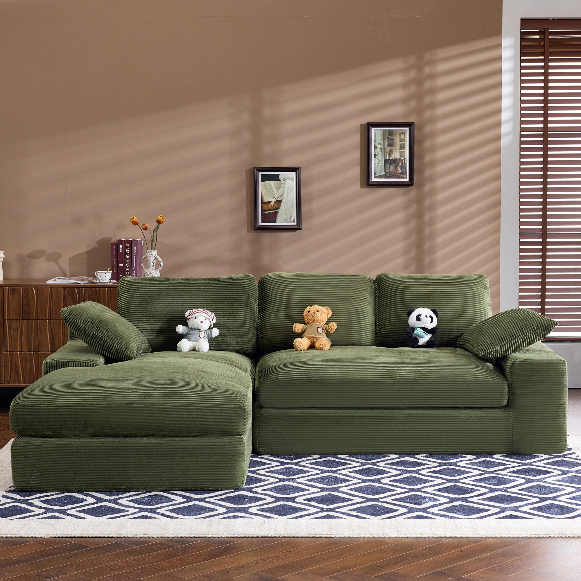 Green corduroy sofa with plush cushions and pillows, styled with stuffed toys. Compact and stylish for modern home interiors.