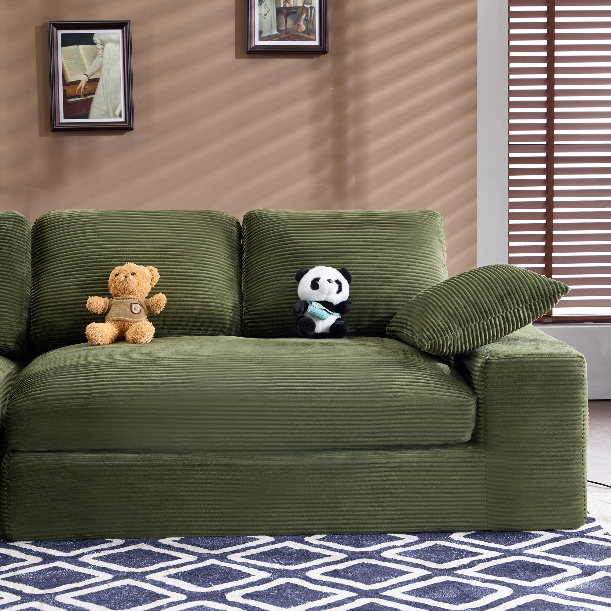 Green corduroy sofa with foam-filled cushions and pillows, placed in a cozy room with wall art and wooden blinds for a warm ambiance.