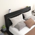 Close-up of Queen Floating Bed Frame headboard with phone slot and side shelf. Modern black wood finish with soft pillows and cushions.