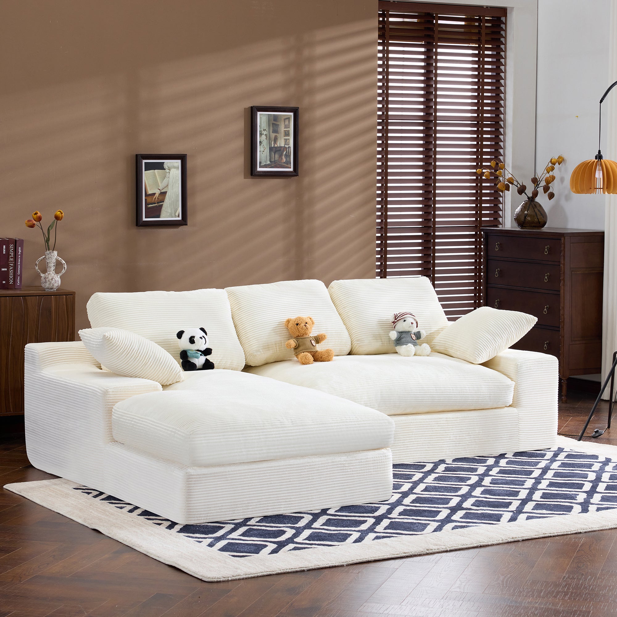Angled view of White Corduroy Sofa with 3 back cushions and 2 pillows, styled with plush toys and a geometric rug.