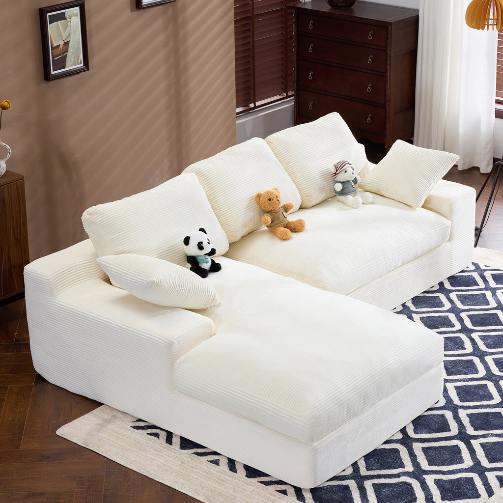 Side angle of White Corduroy Sofa showing soft corduroy texture, 3 back cushions, and 2 pillows on a blue patterned rug.