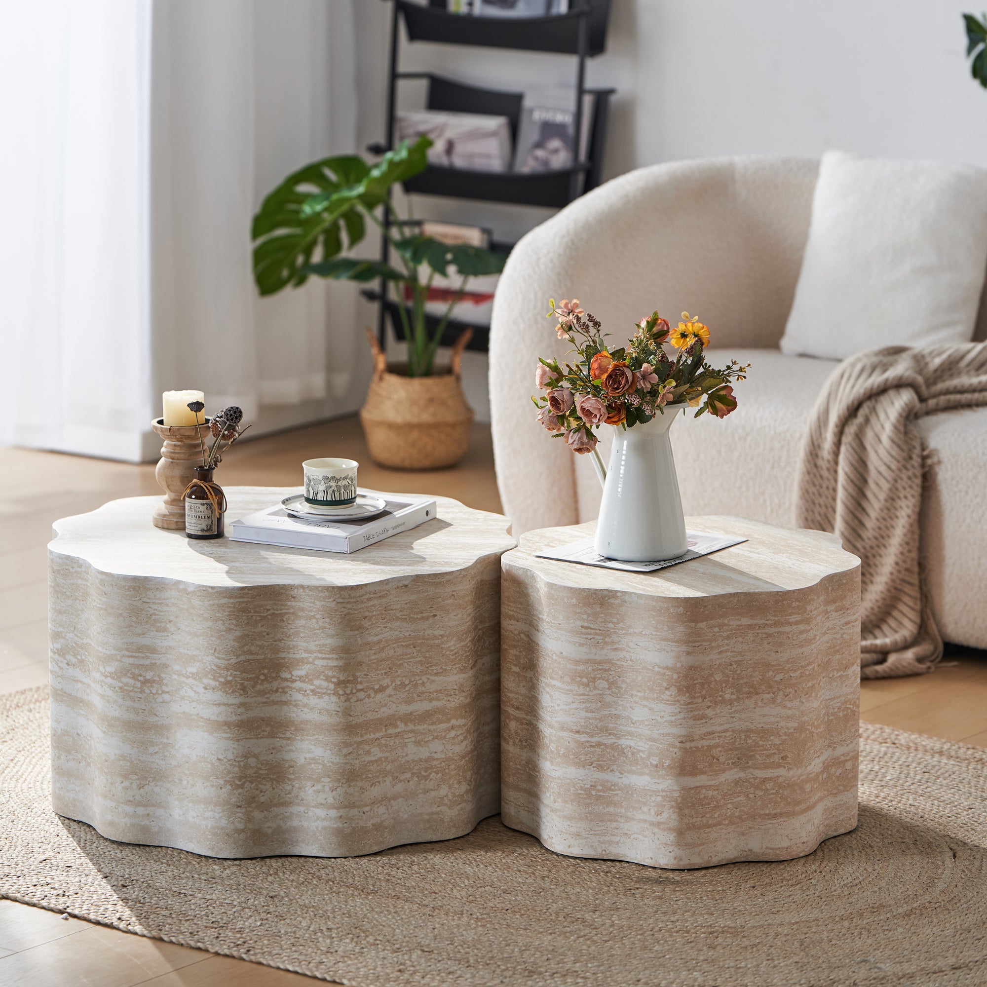 Two modern, scalloped, faux-travertine nesting coffee tables with beige marble-like textures on a textured rug.