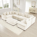 Oversized cream corduroy modular sectional sofa with wide armrests and a matching ottoman in a bright living room.