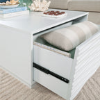 Open drawer of the white coffee table revealing spacious storage with books and a pillow, perfect for organizing living room essentials.