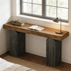 Contemporary console table with a thick wood top and arched, dark charcoal-textured pillar bases by a window.
