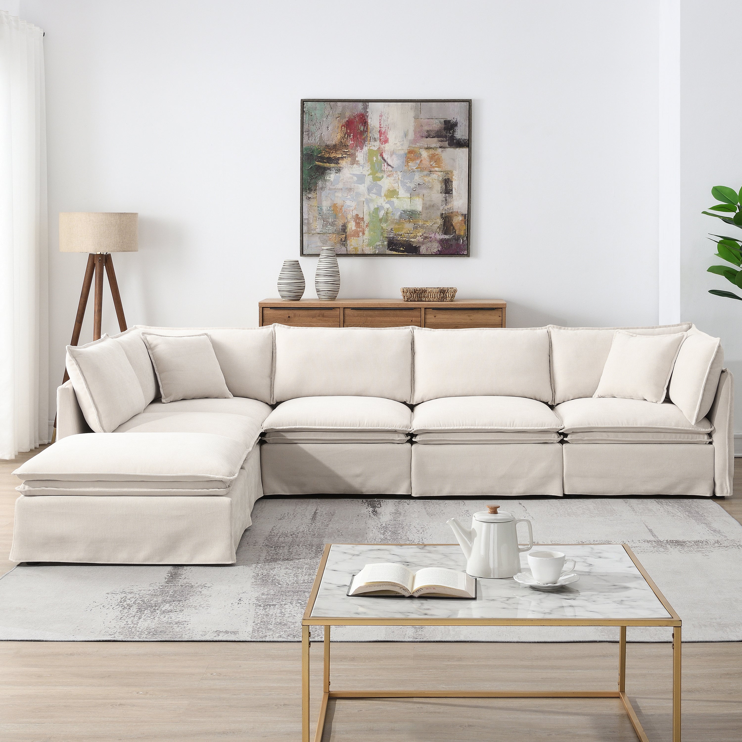 L-shaped modular sectional sofa with ottoman in a neutral-toned living room, designed for comfort and flexibility.