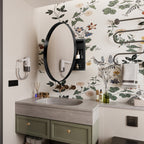 Round Black Metal Medicine Cabinet with Mirror and side storage mounted above a gray sink in a floral-themed bathroom.