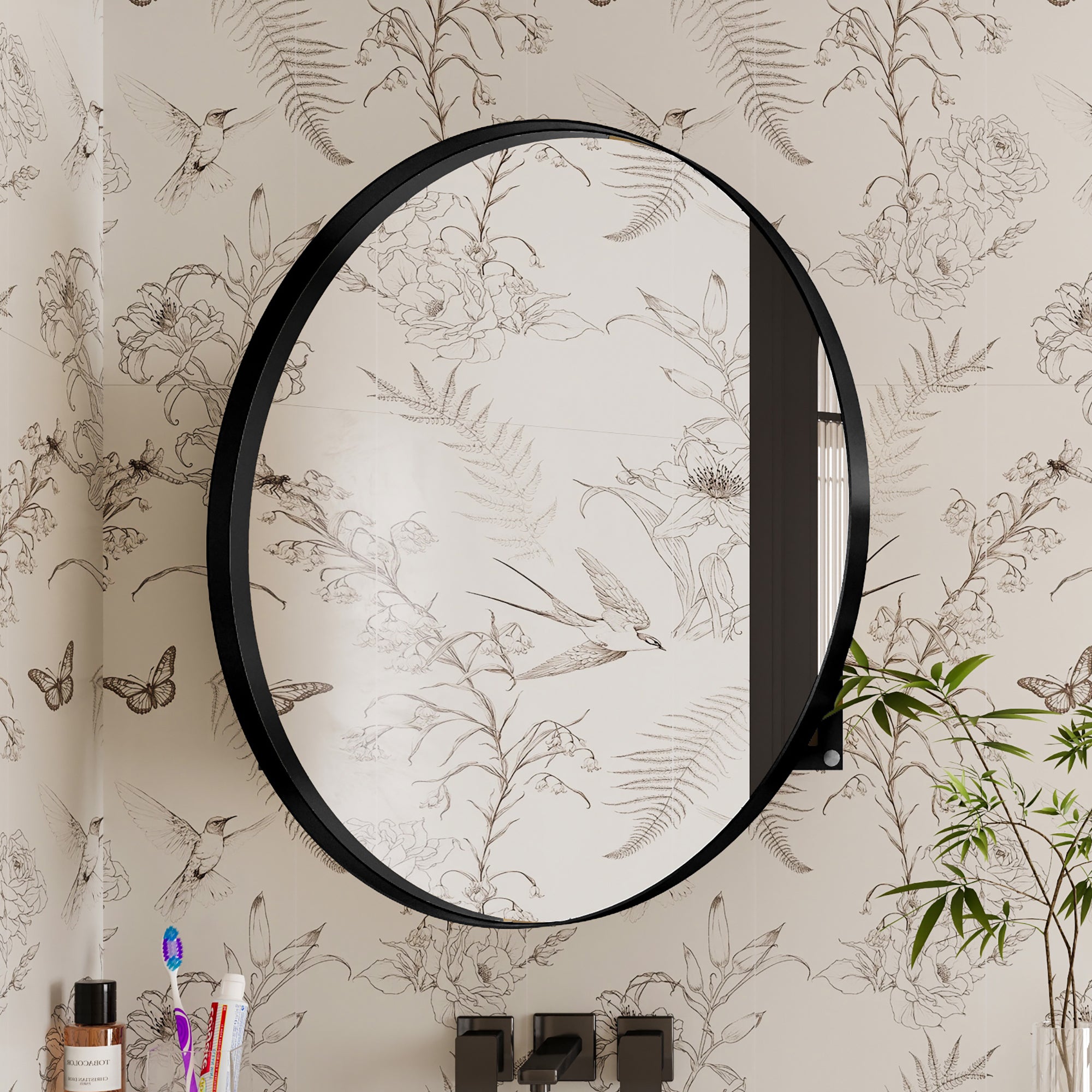 Round Black Metal Medicine Cabinet with Mirror closed, reflecting floral wallpaper in a stylish bathroom setting.