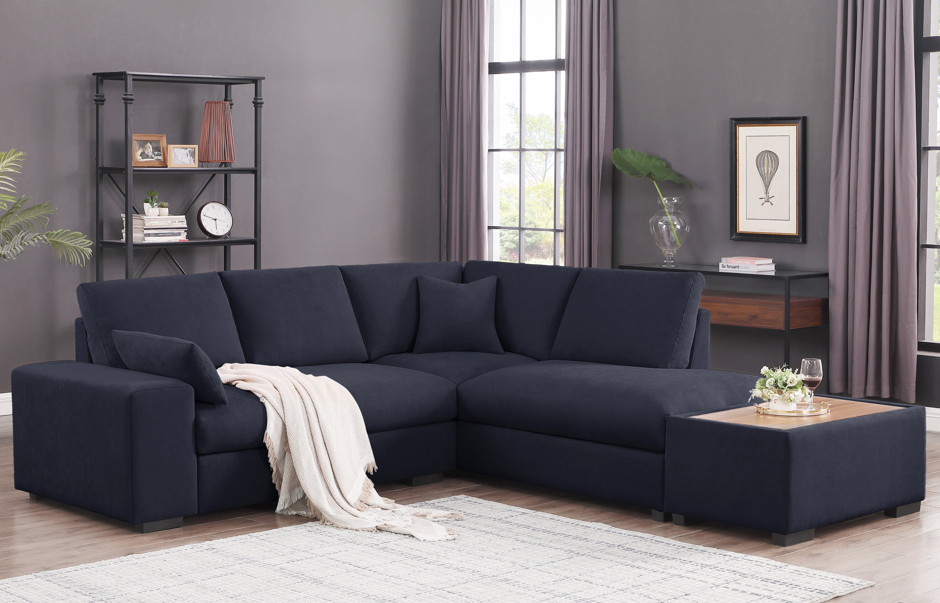 Dark gray sectional sofa with throw blanket and ottoman. Features chaise, console, and wood-top ottoman for modern comfort.