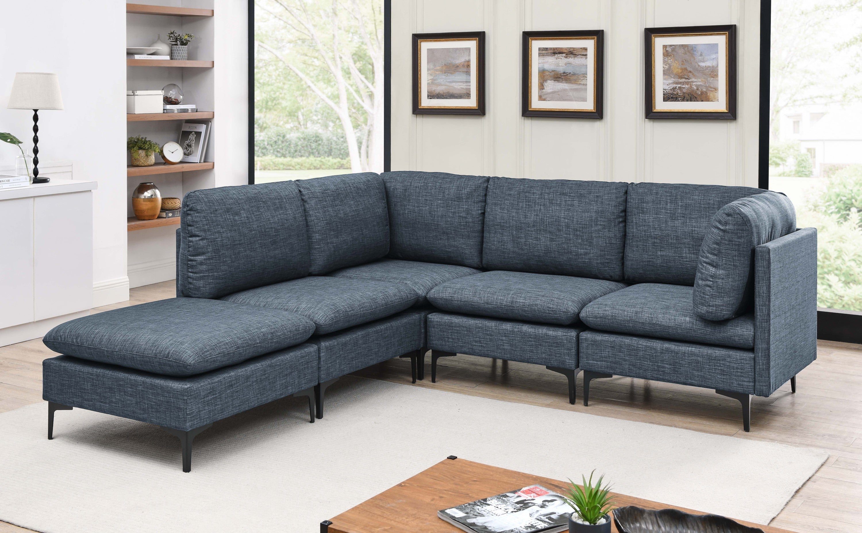 Modern navy blue linen modular sectional sofa with plush cushions and sleek black metal legs in a bright living room.