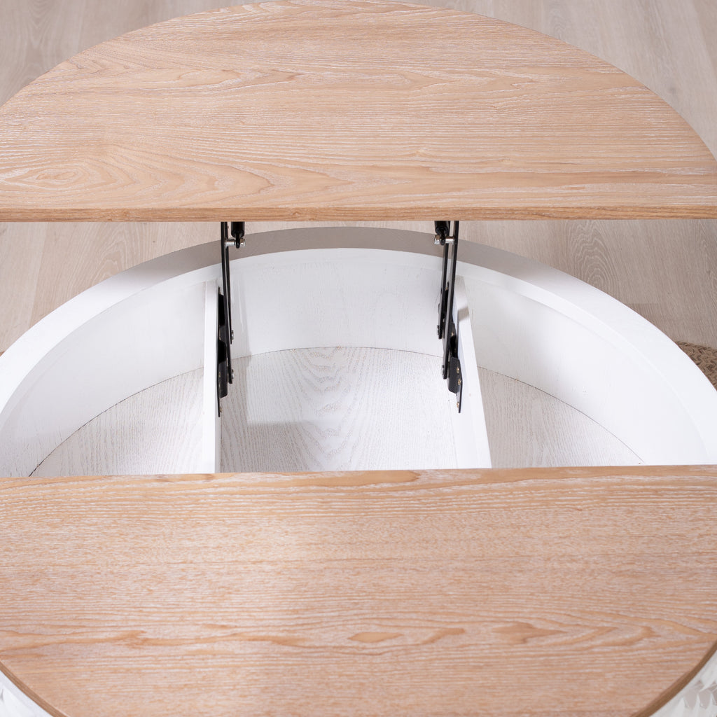 Top-down view of open lift-top round coffee table showing internal storage and white carved base.
