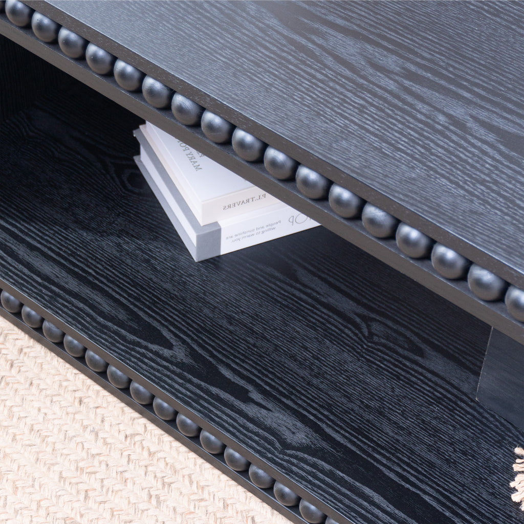 Detail of Black Beaded Coffee Table’s open shelf with books and beaded trim, emphasizing storage and decorative features.
