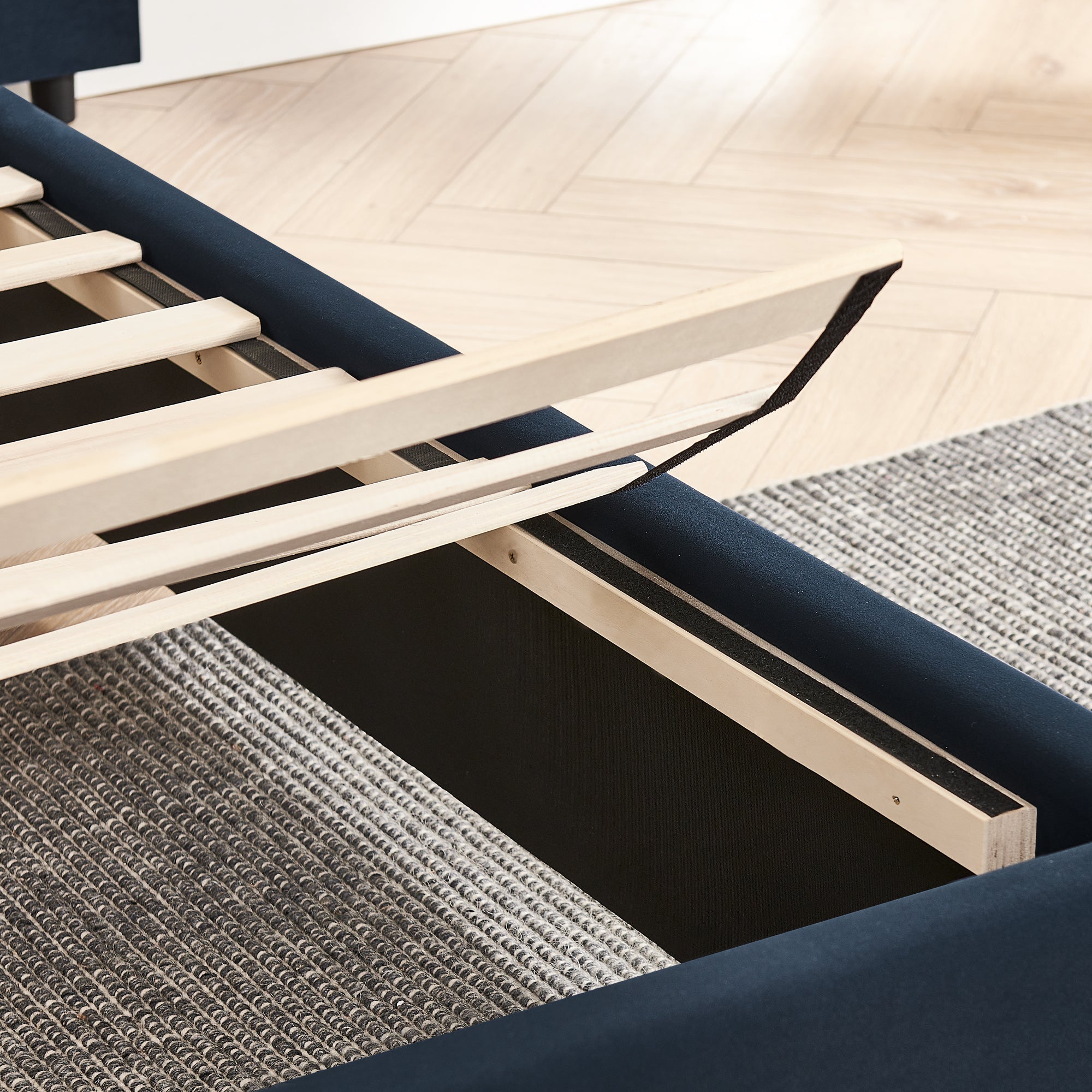 Under-bed storage compartment with lift-up slats on queen upholstered velvet bed frame for practical bedroom organization.