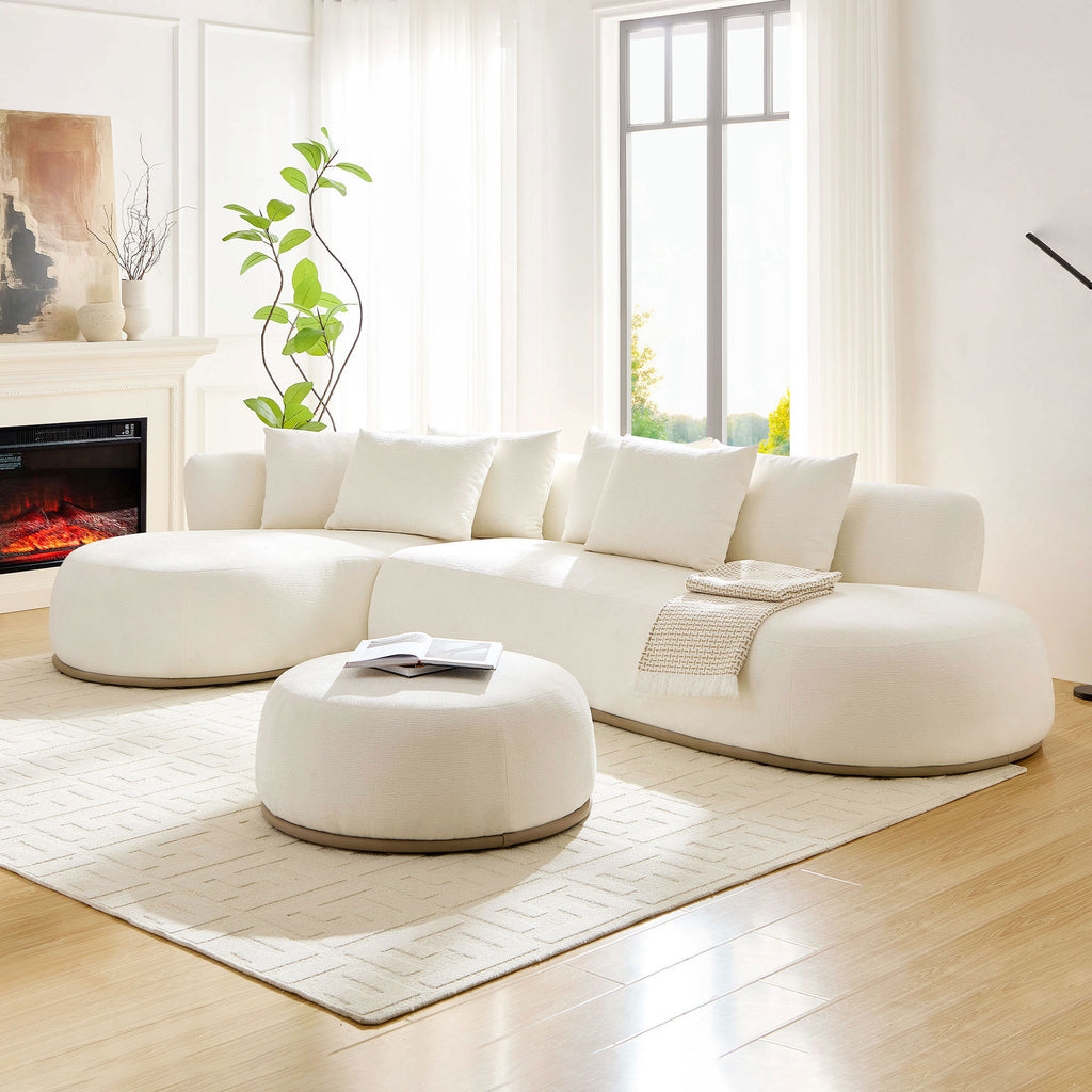 Beige L-shape sectional sofa with ottoman in a bright living room, styled with a fireplace and soft area rug for a warm ambiance.