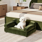 Small olive green velvet pet bed with tufted detailing and rolled arms, featuring a white dog sitting on the cushion.