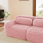 Close-up of left section of pink modular plush sofa with ottoman, showing soft armrest and supportive back cushion in cozy setting.