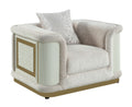 Contemporary beige fabric accent chair with gold-accented frame, textured side panels, and a patterned throw pillow.