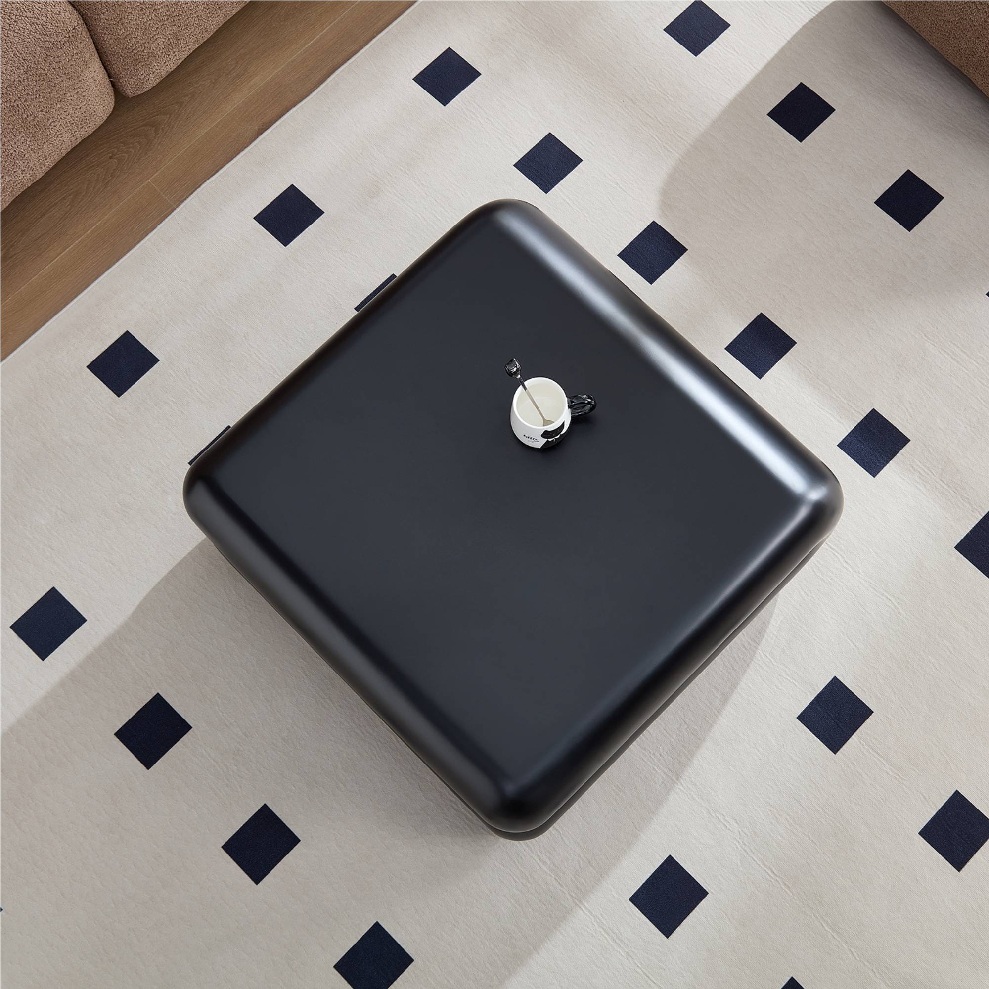 Overhead view of square black fiberglass coffee table with smooth finish, highlighting its sleek surface and compact dimensions.