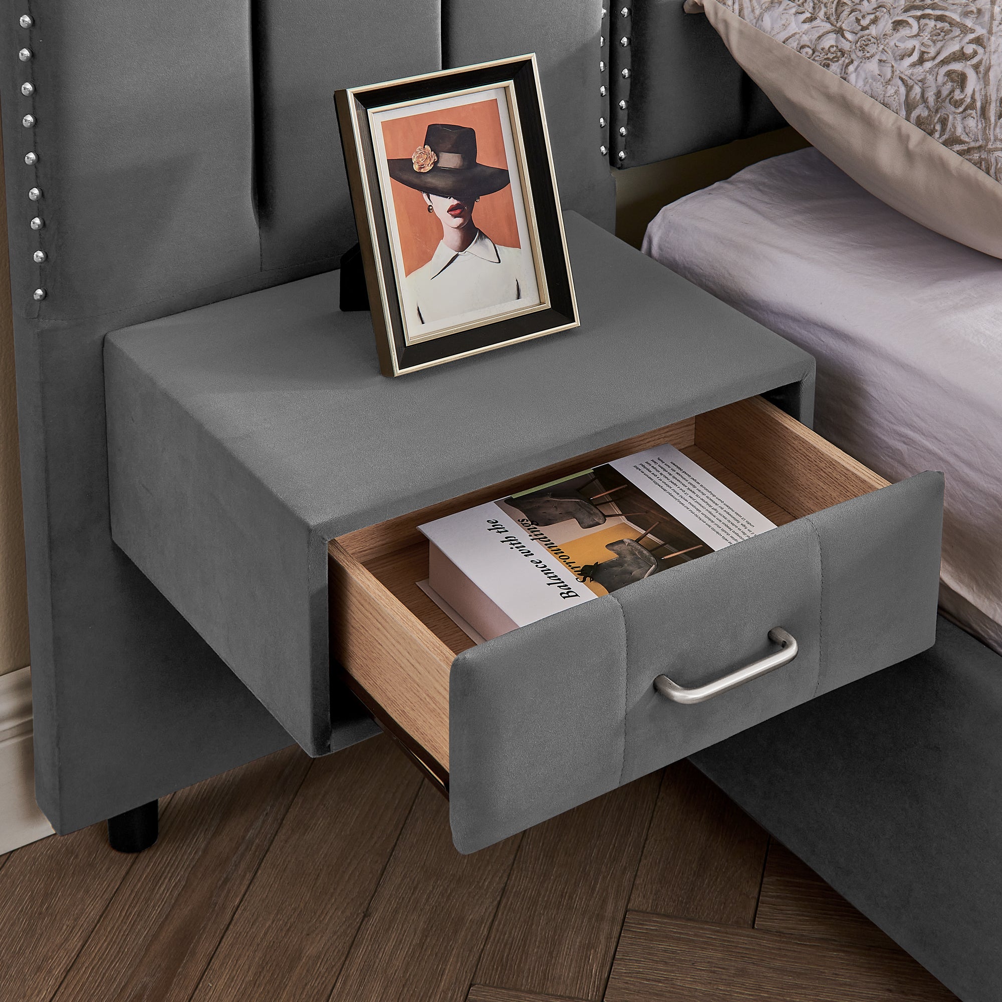 Open drawer of floating nightstand attached to velvet queen bed frame, showing storage space and modern handle design.