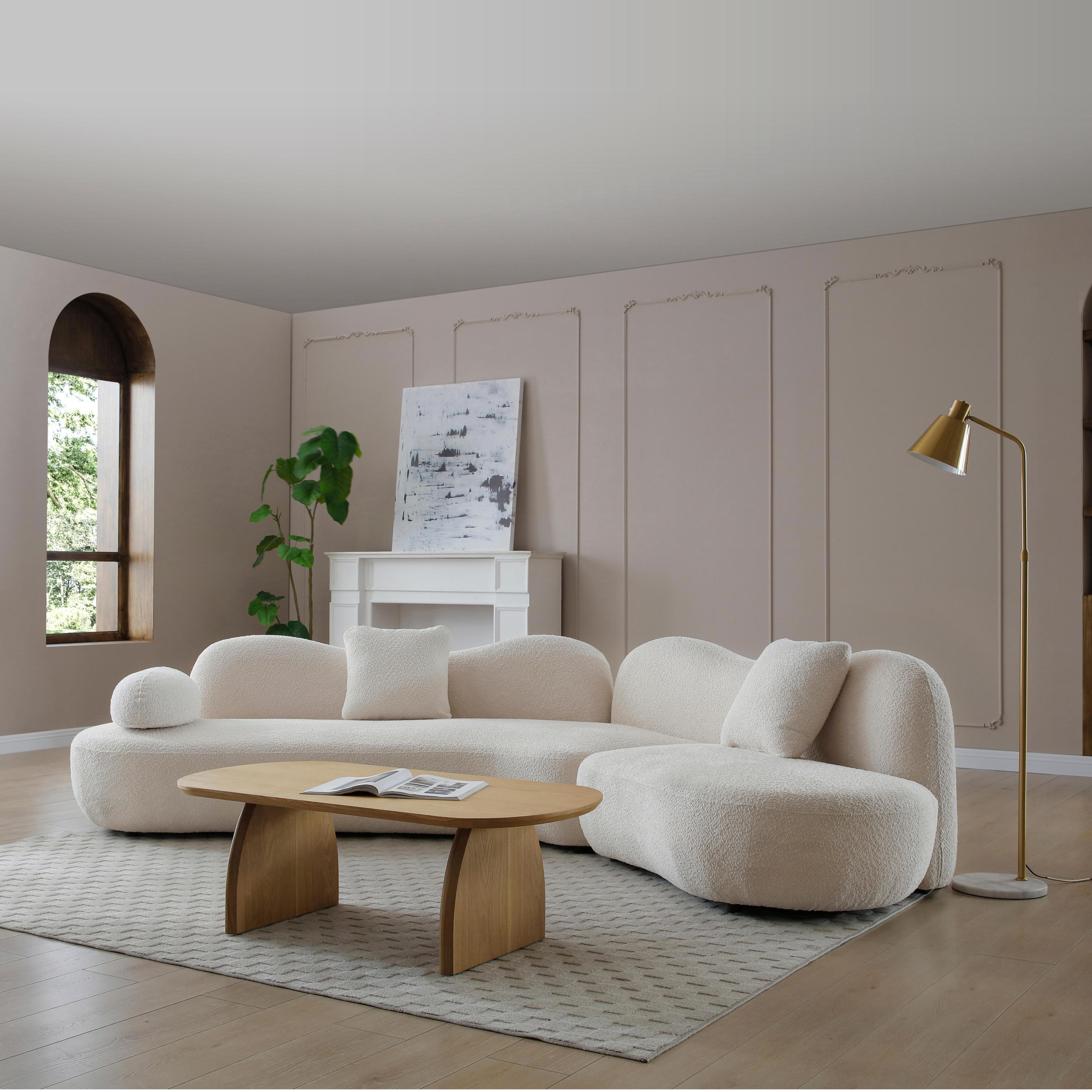 White boucle 5-seater curved sectional sofa with wood frame, paired with a wooden coffee table and gold floor lamp in a cozy living space.
