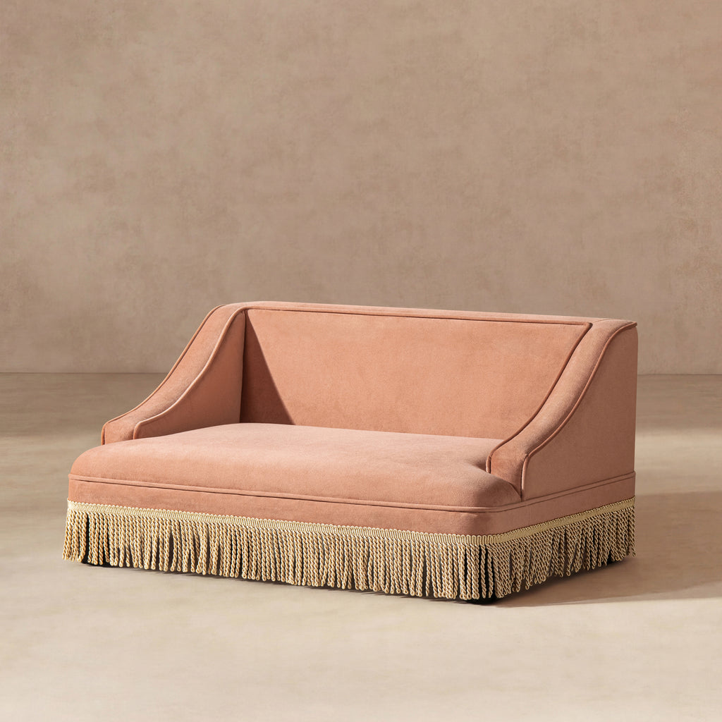 Peach orange performance velvet pet sofa with elegant rolled arms and a decorative cream-colored fringe base.