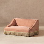 Peach orange performance velvet pet sofa with elegant rolled arms and a decorative cream-colored fringe base.