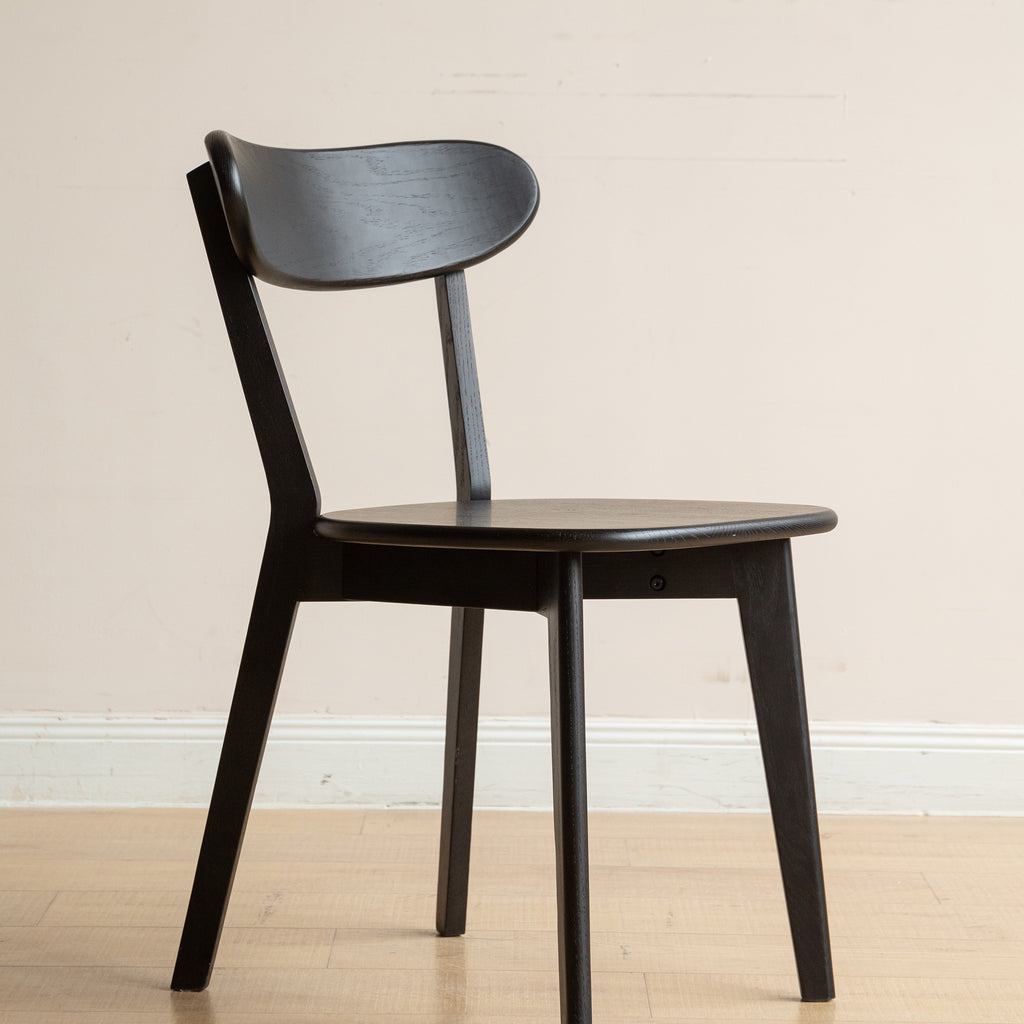 Durable black wood dining chair made from FAS-grade solid oak, shown in a natural indoor setting with hardwood flooring.