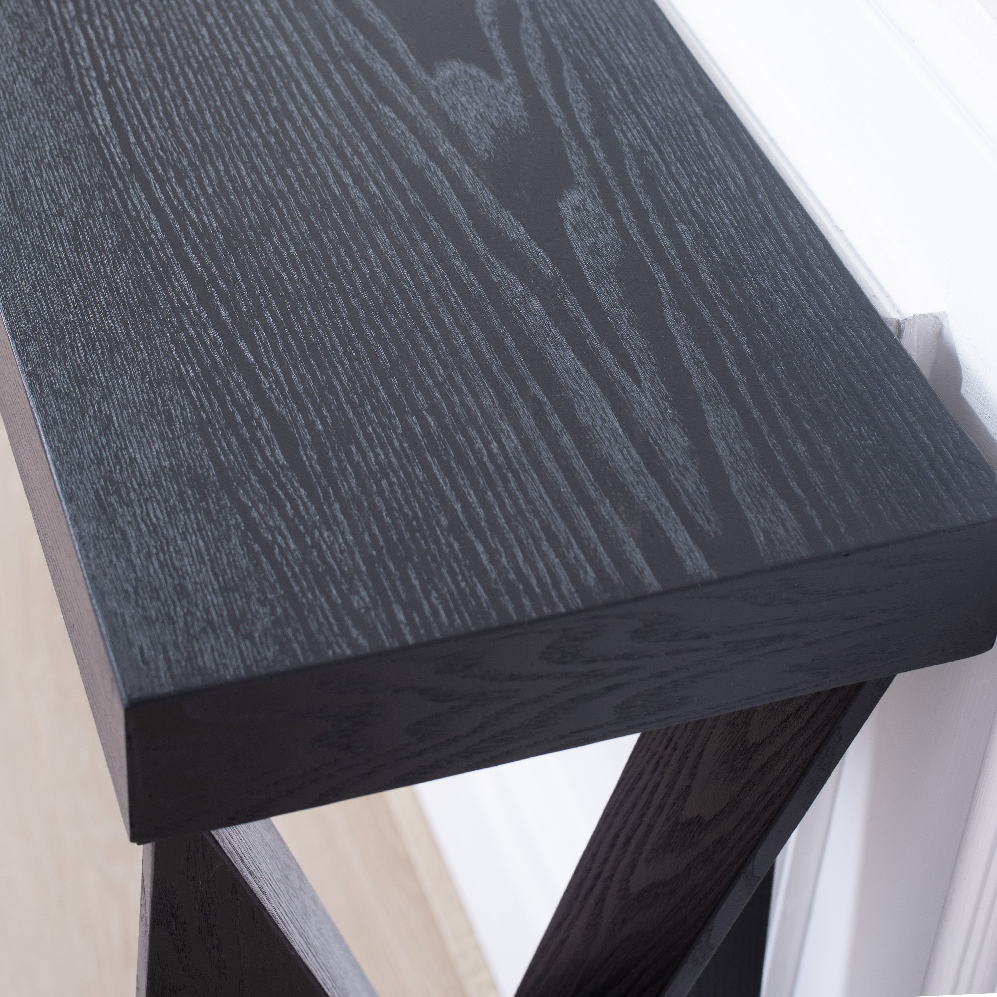 Close-up of black wood grain tabletop on modern console table, highlighting its textured finish and craftsmanship.