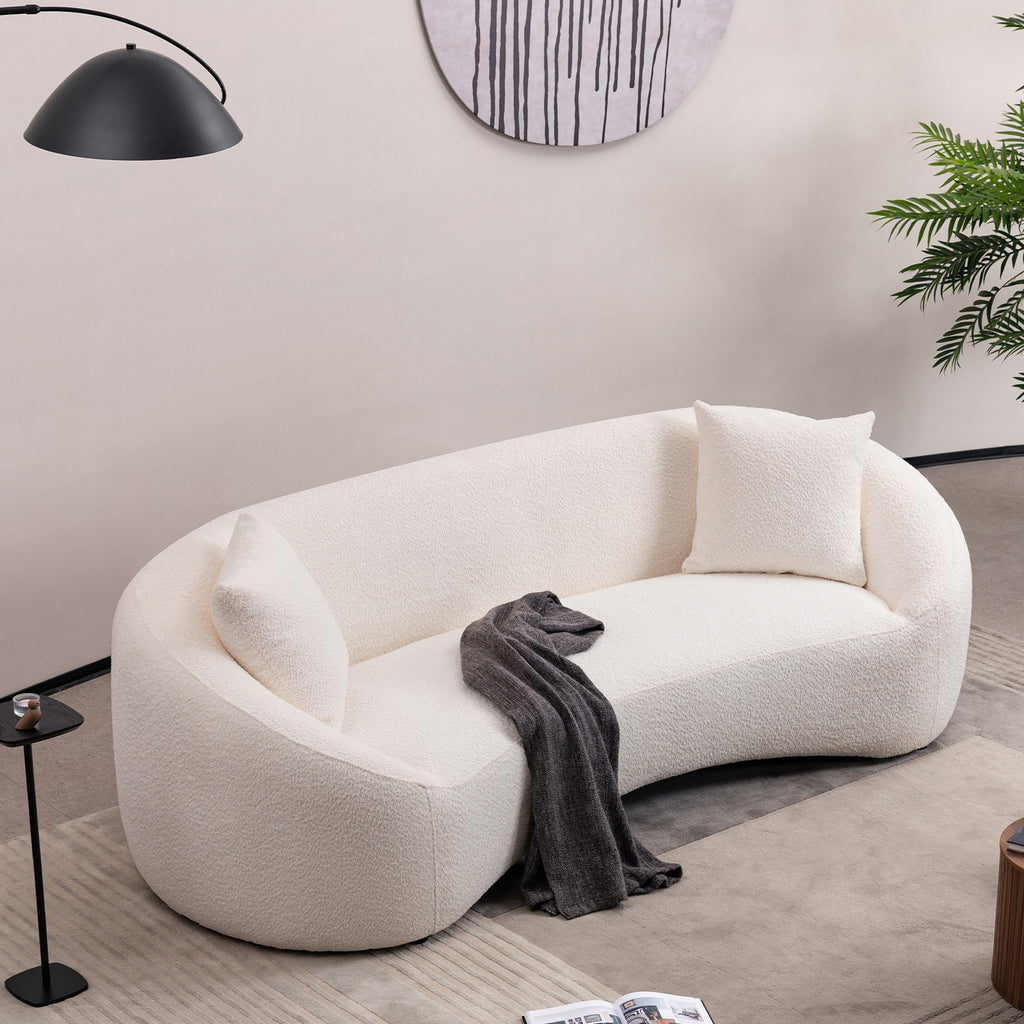 Angled overhead view of minimalist white curved sofa in a stylish living room with cozy decor elements.