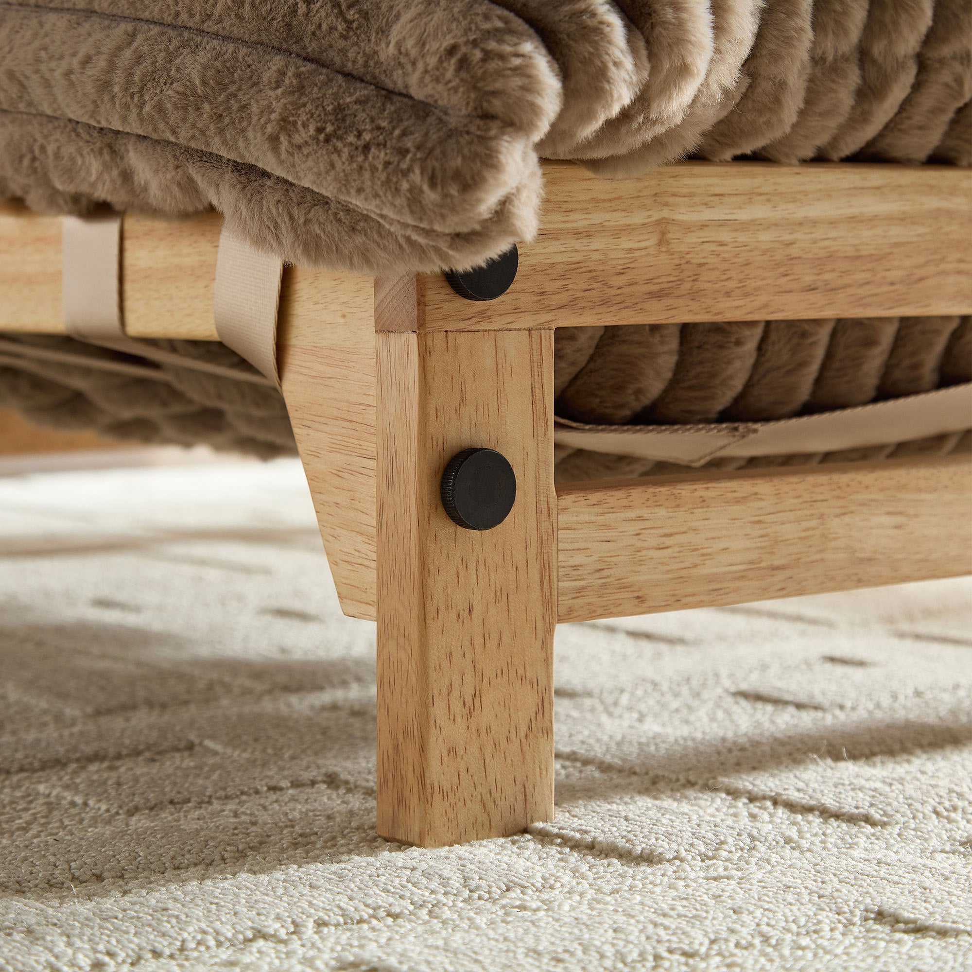 Detail of wooden leg and frame construction on corduroy sofa chair, emphasizing durability and quality craftsmanship.