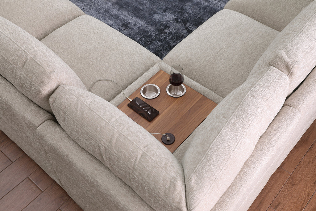 Top view of center console on beige chenille sectional sofa with wood tray, cupholders, and USB charging port.