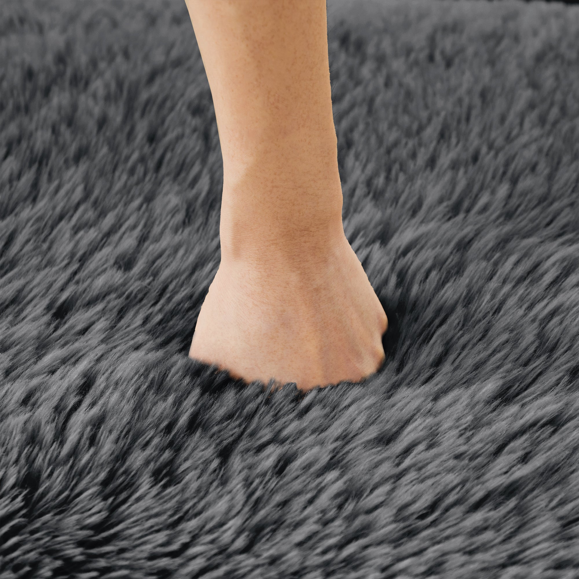 Hand pressing into the plush surface of the Dark Grey Modular Sofa, demonstrating the softness and comfort of the fabric.