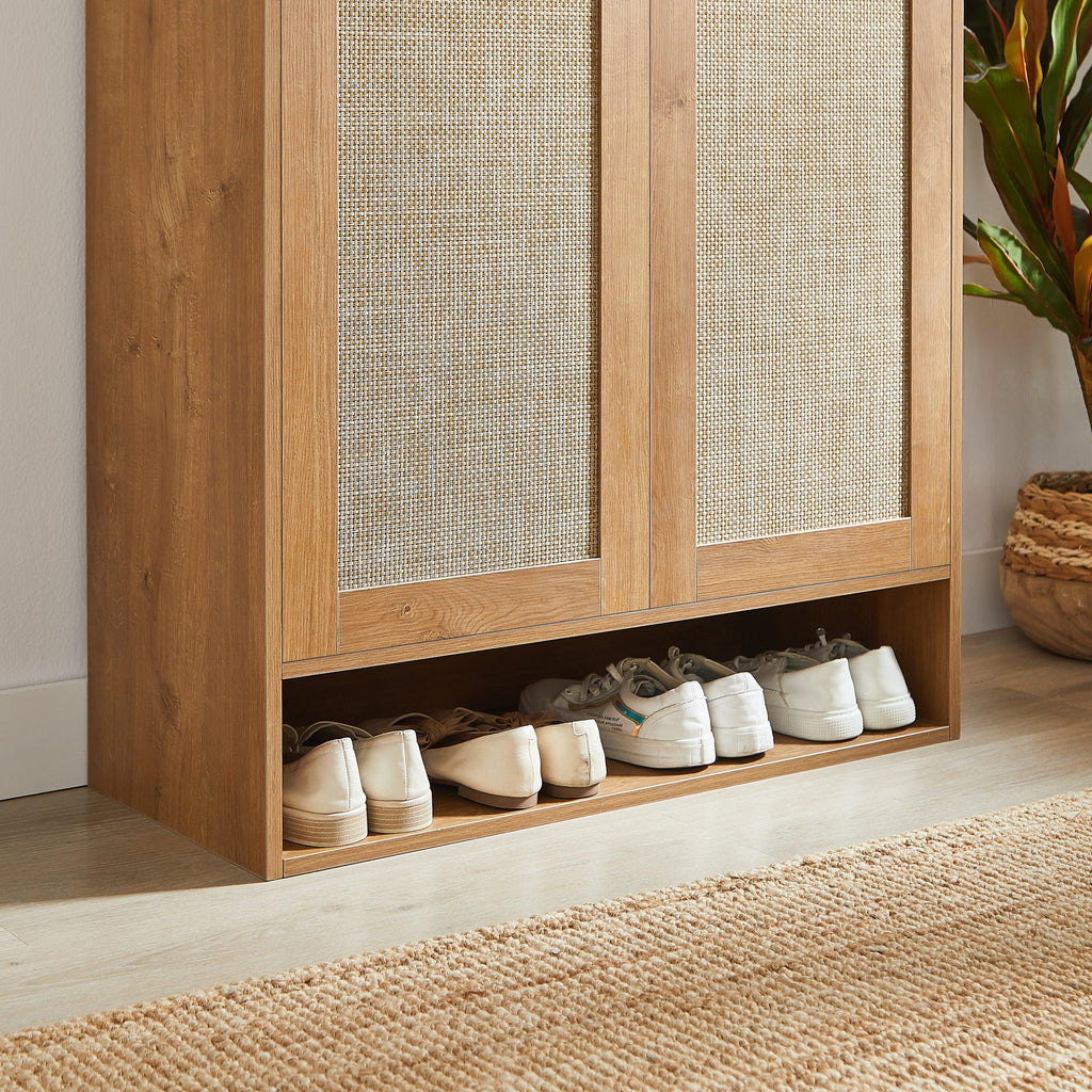 Bottom open shelf of rattan shoe cabinet storing shoes. Extra storage space ideal for frequently used footwear.