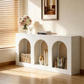 White console table with three arched cubbies, featuring minimalist design, decorative vases, and books.