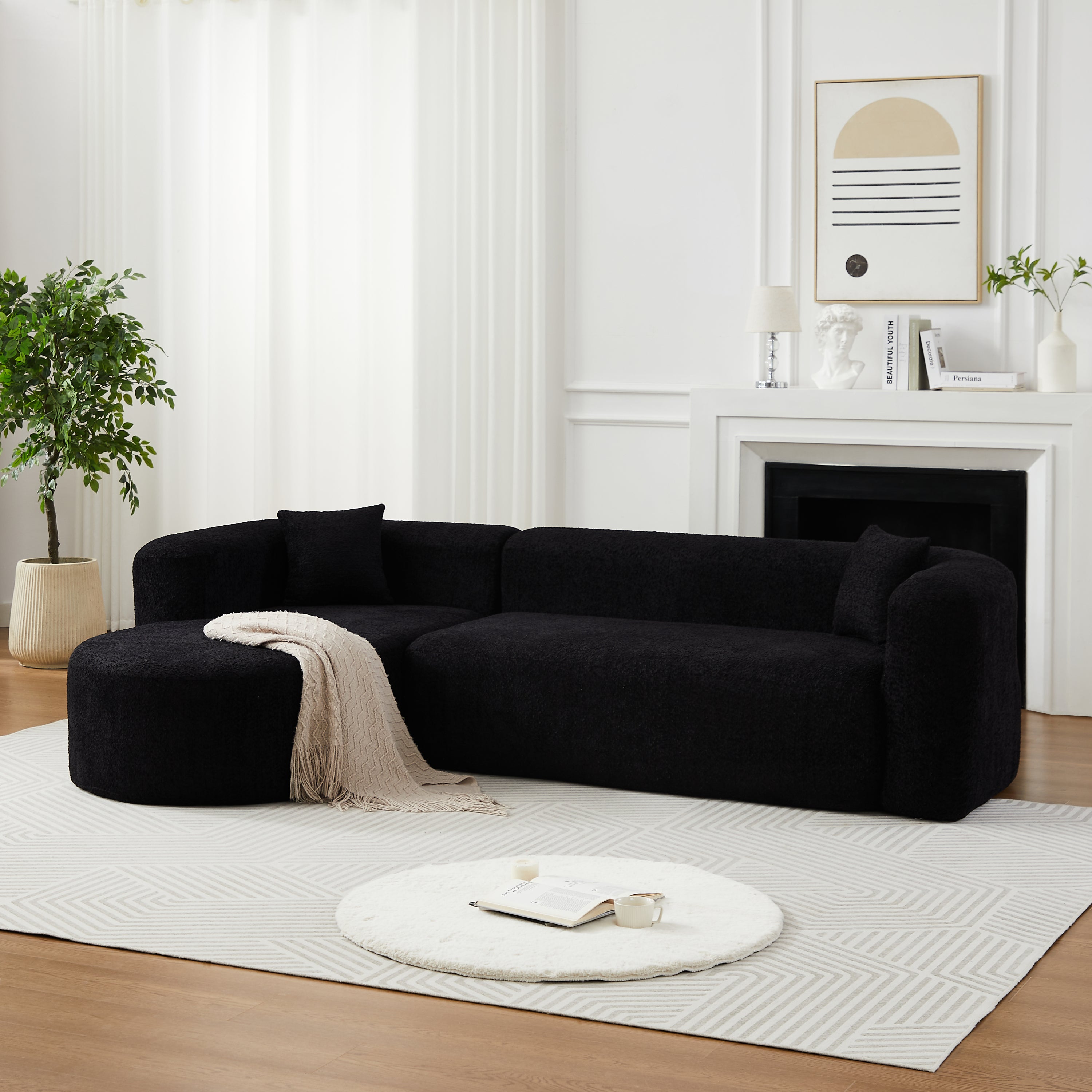 Modular sectional sofa with curved back in black chenille fabric, styled in a modern living room with white walls and minimalist decor.