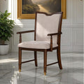 Transitional dining arm chair with beige upholstery, dark cherry wood frame, and gold capped legs in elegant room setting.