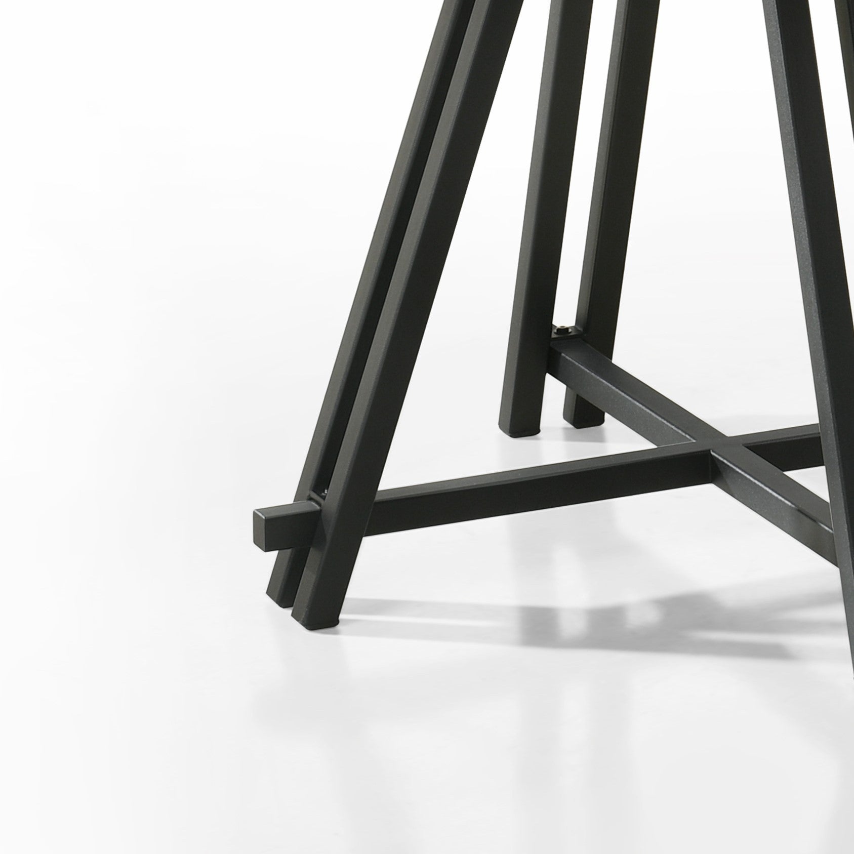 Detailed view of the black metal base of the Round Oak Dining Table, emphasizing its sturdy geometric design.