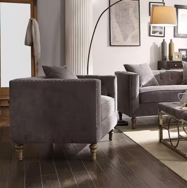 Sidonia Gray Velvet Chair with Pillow in modern living room setup, featuring nailhead trim and turned wood legs for relaxed seating elegance.