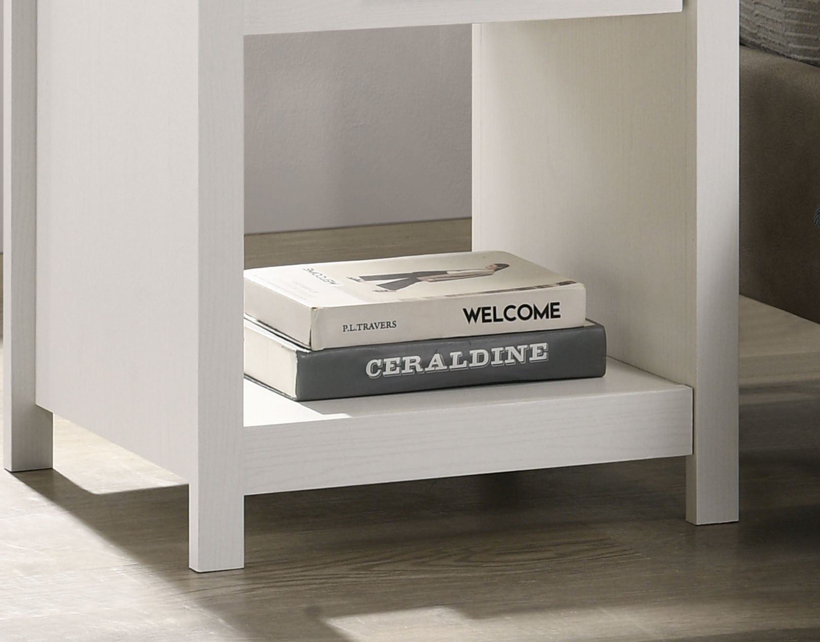 Bottom shelf of Celeste 1-Drawer Nightstand holding books. Open storage space enhances functionality in compact design.