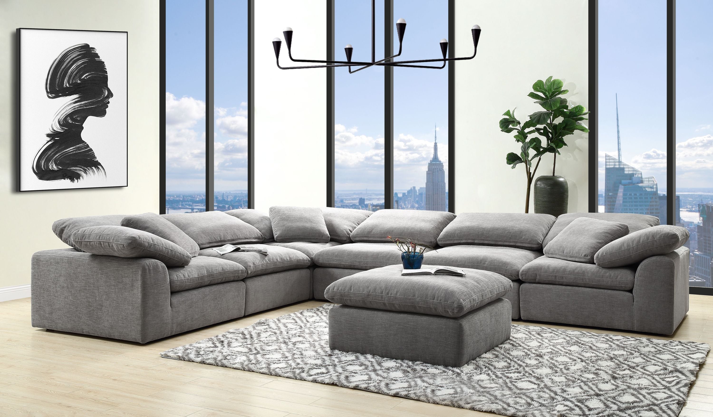 Modern gray linen modular sectional sofa with deep, plush seating and matching ottoman on a patterned area rug.