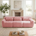 Plush pink modular sectional sofa with fuzzy fabric and three bolster pillows in a cozy, bright living room.