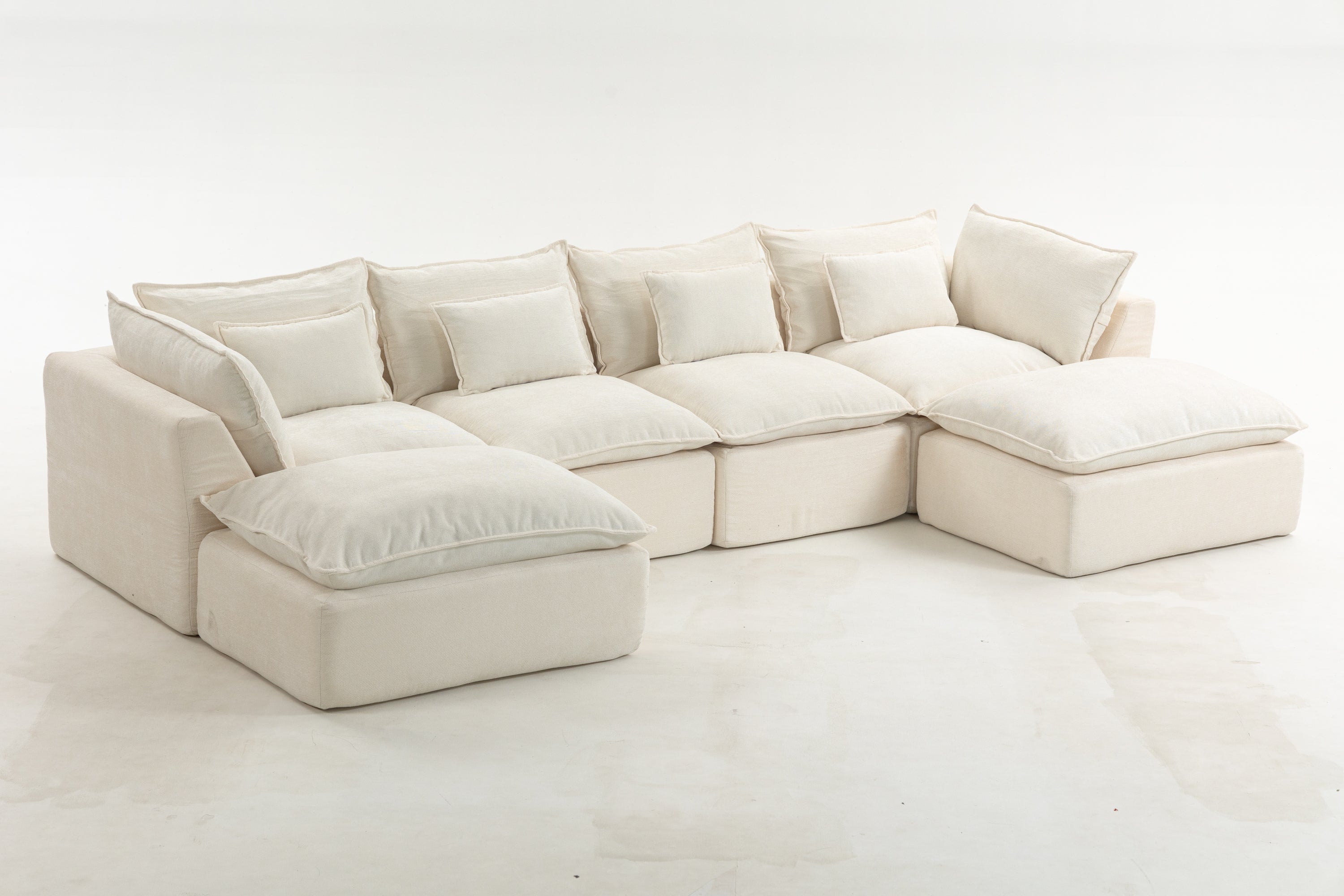 Cloud couch-style oversized modular sectional sofa with wide and deep seats. Includes 4 seats and 2 ottomans in a neutral cream fabric.