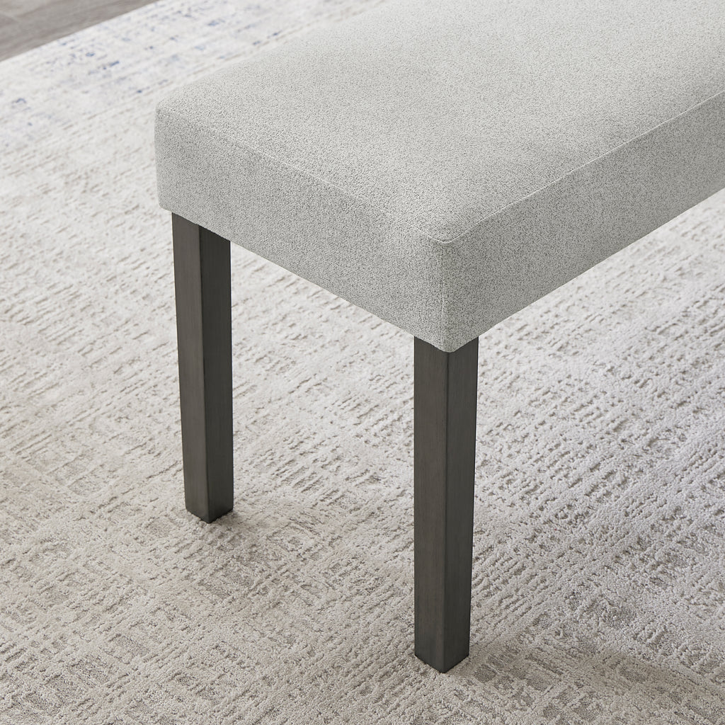 Detail of Selena Dining Set bench with textured light gray fabric and sturdy black legs, designed for modern dining areas.