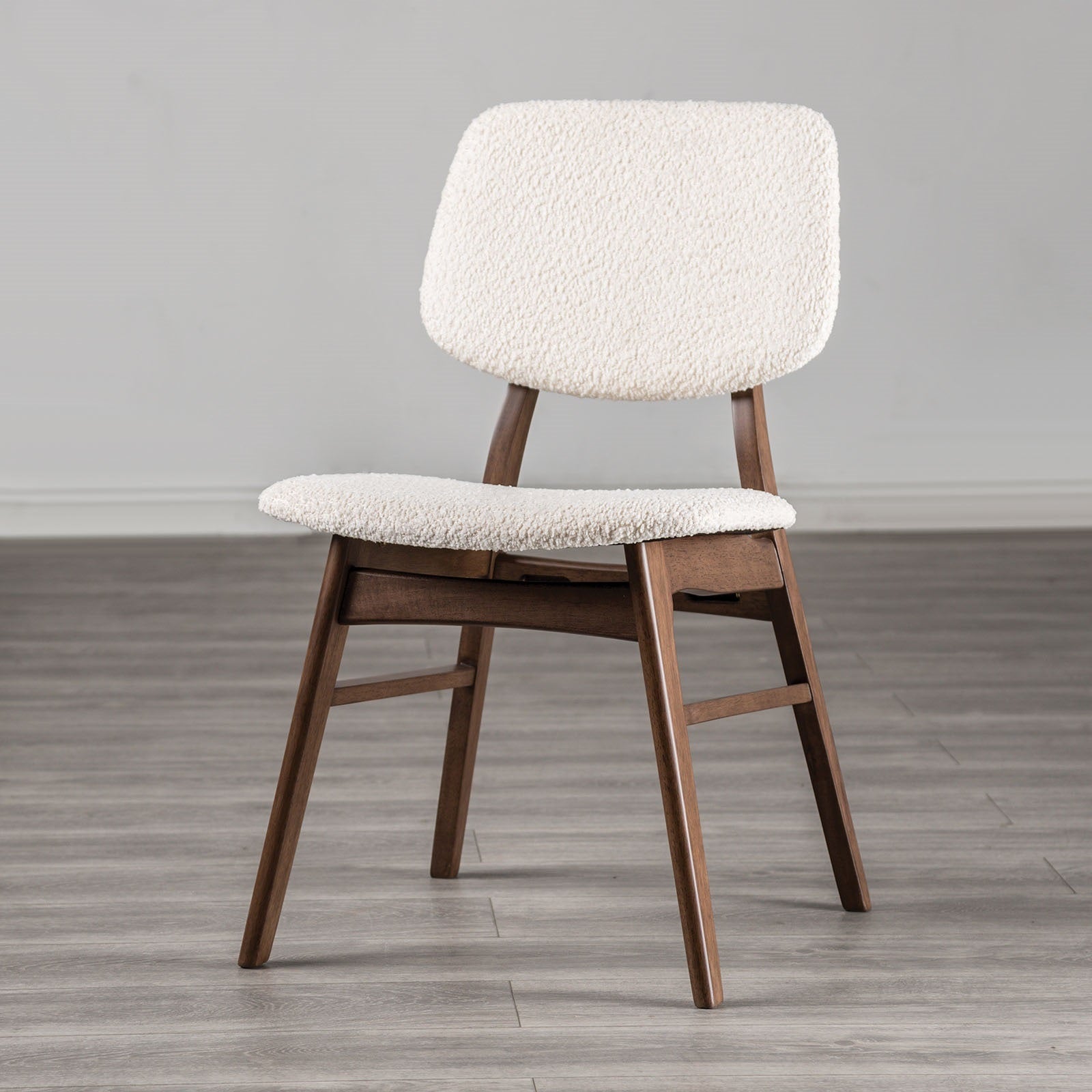 Elegant mid-century dining chair with angled walnut legs and soft beige padding, suitable for stylish dining room setups.