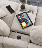 Tablet and wine glass on beige chenille sectional sofa armrest with USB charging port and cupholders for convenience.