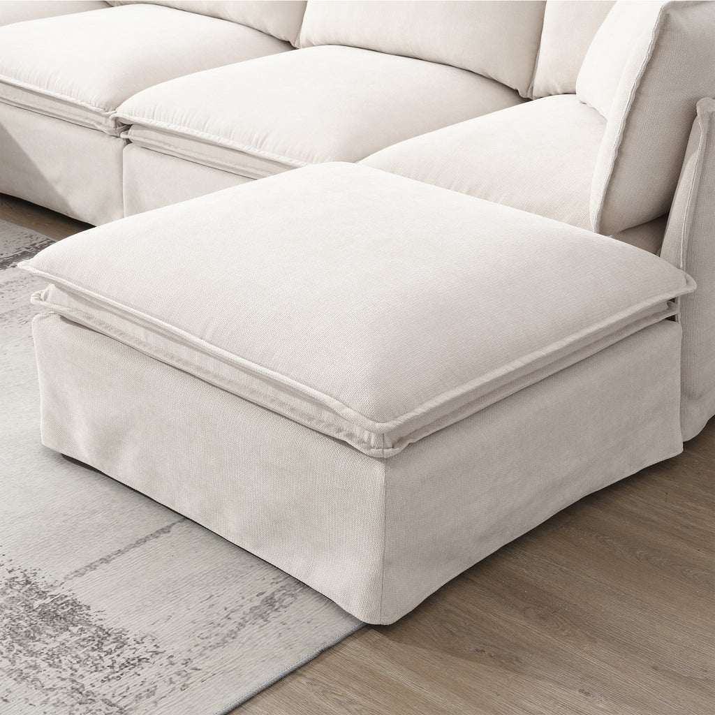 Close-up of movable ottoman from modular sectional sofa, upholstered in beige fabric with plush cushioning for added comfort and flexibility.